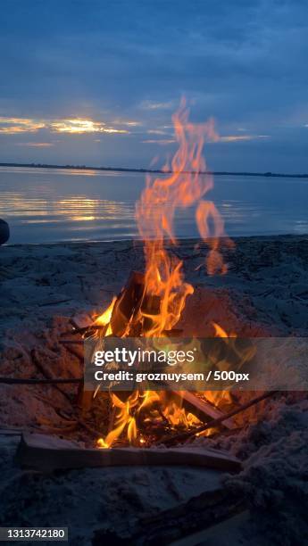 close-up of bonfire at beach against sky during sunset - bonfire beach stock pictures, royalty-free photos & images