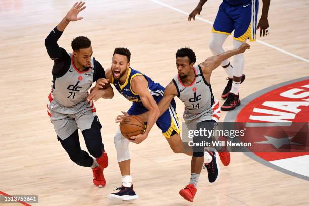 Stephen Curry of the Golden State Warriors dribbles in front of Daniel Gafford and Ish Smith of the Washington Wizards during the second half at...