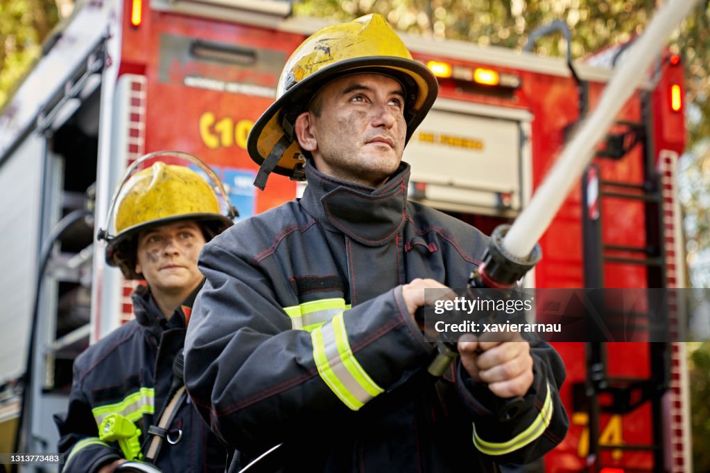 Action Portrait von männlichen und weiblichen Feuerwehr Schlauch Team