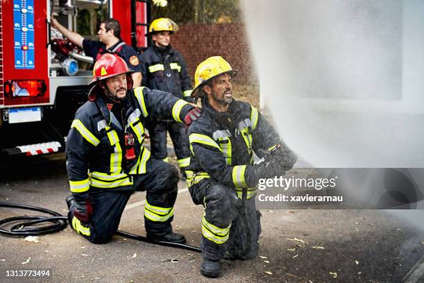 mature male hose team working together at emergency site - fire truck stock pictures, royalty-free photos & images