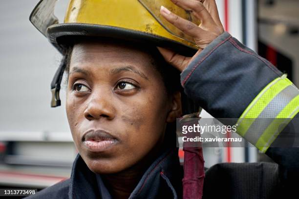 candid close-up of black female firefighter and helmet - black firefighter stock pictures, royalty-free photos & images