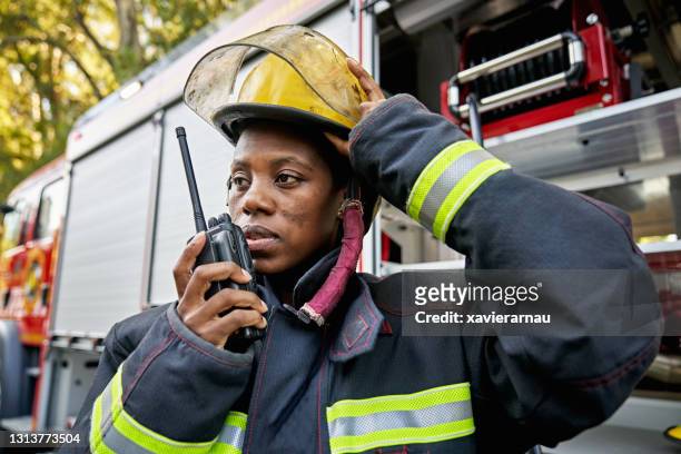 zwarte vrouwelijke brandweerman die walkie-talkie met behulp van - brandweerman stockfoto's en -beelden