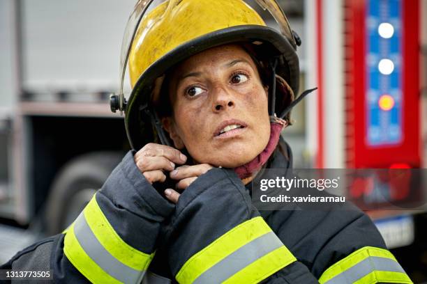 retrato sincero de la mujer bombero poniéndose casco - firefighter fotografías e imágenes de stock