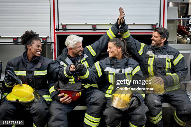 alto cinque e pugno da diversi gruppi di vigili del fuoco - firefighters foto e immagini stock