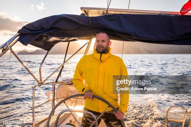 man at the steering wheel on the yacht at sunset. luxury vacation at the sea - cruise crew stock pictures, royalty-free photos & images