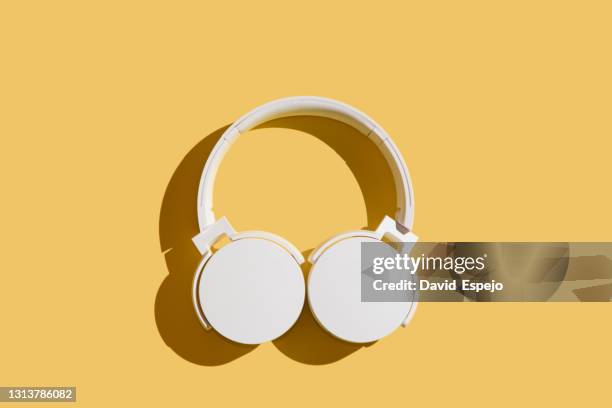 white headphones on a orange background - in ear headphones stock-fotos und bilder