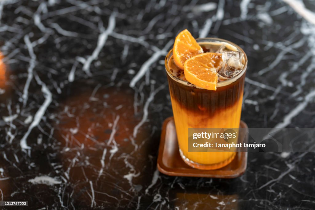 Americano coffee mixed with orange juice with orange slices on the glass.