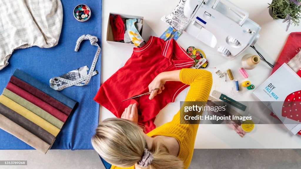 Top view of woman sewing face masks from T-shirt, coronavirus and upcycling concept.