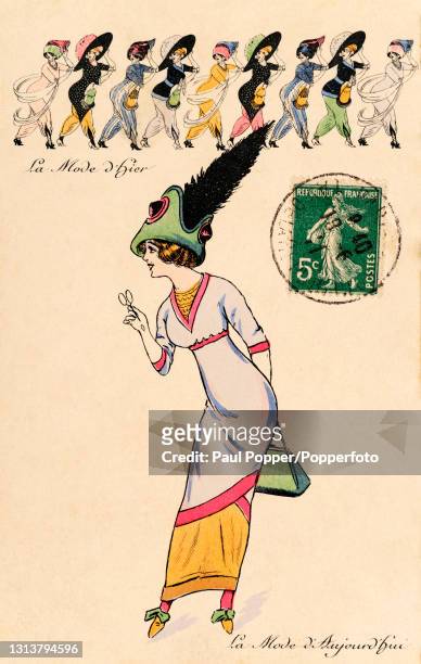 Postcard showing a woman wearing a light blue high waisted dress with a long, narrow skirt, a green, shaped hat with large black feather and a...