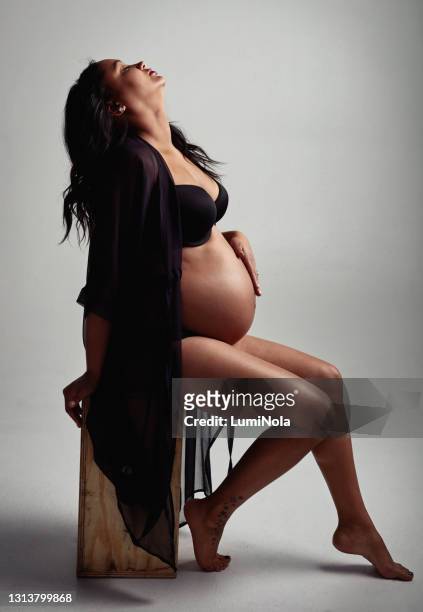 projectile recadré d’une femme enceinte posant dans la lingerie sur un fond gris - fond studio photo photos et images de collection