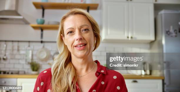 mature woman having a video call in kitchen - stay at home saying stock pictures, royalty-free photos & images