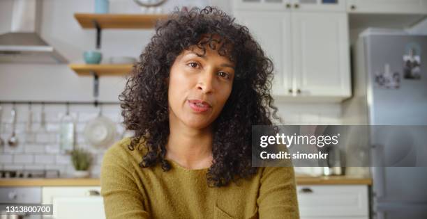 rijpe vrouw die een videogesprek in keuken heeft - hoofd schuin stockfoto's en -beelden