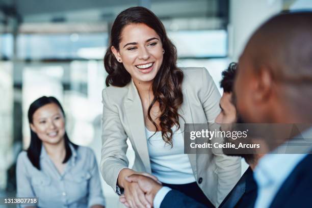 ontsproten van een jonge onderneemster die handen met een collega schudt tijdens een vergadering in een modern bureau - asian shaking hands stockfoto's en -beelden