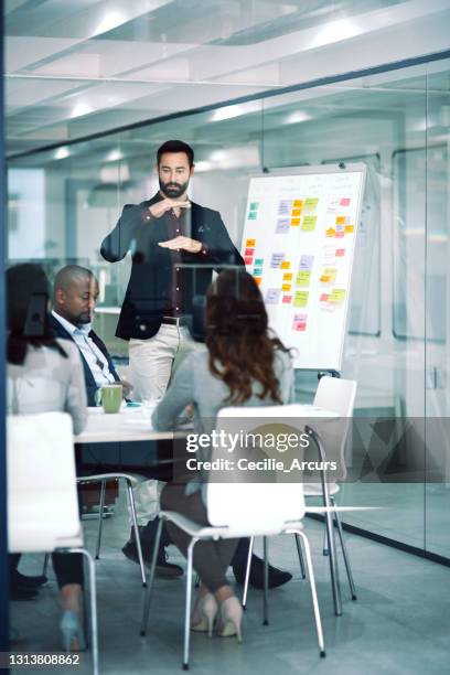 scatto di un uomo d'affari che consegna una presentazione ai suoi colleghi nella sala riunioni di un ufficio moderno - confidence studio shot foto e immagini stock