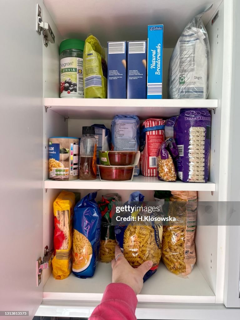 Hand reaching for the pasta in the kitchen cabinet