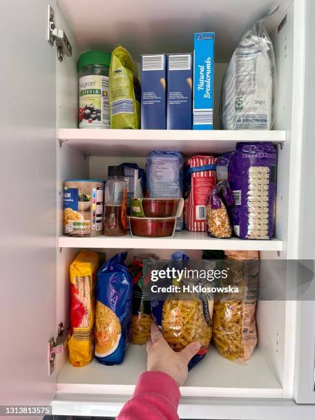 hand reaching for the pasta in the kitchen cabinet - organised shelves bildbanksfoton och bilder