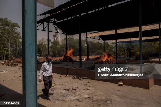 An elderly man walks amid multiple burning funeral pyres of patients who died of the Covid-19 coronavirus disease at a crematorium on April 22, 2021...