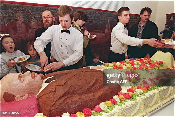 Waiters cut and offer 30 March 1998 in a Moscow restaurant pieces of a life-size cake depicting Russian Bolshevik revolutionary leader Vladimir...