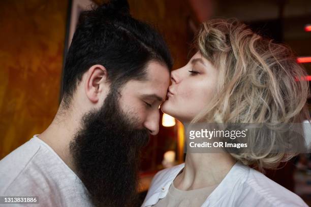 woman kissing forehead of hipster man - affettuoso foto e immagini stock