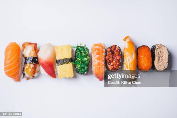 overhead view of variety of sushi on against a white background - maki sushi stock-fotos und bilder