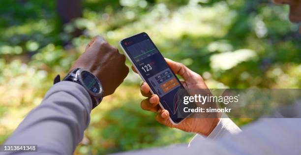 woman using tracker software on smartphone and smart watch - wearable technology stock pictures, royalty-free photos & images