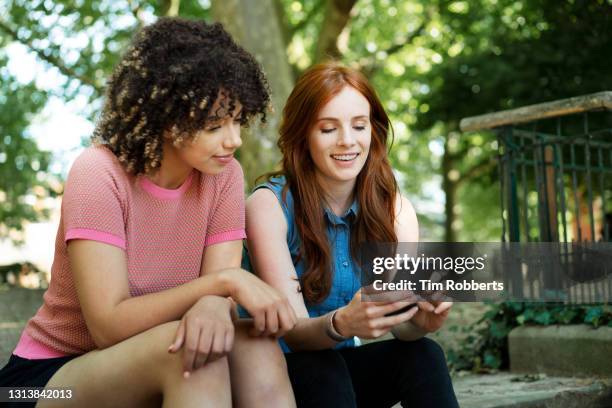 two friends looking at smart phone - light skin black woman stockfoto's en -beelden