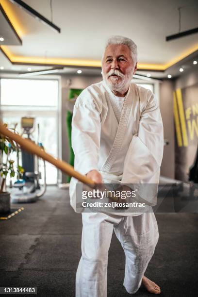 l’homme aîné pratique l’exercice de tai chi dans la gymnastique - arts martiaux photos et images de collection