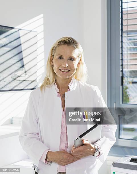 female doctor holding digital tablet, smiling - ärztin stock-fotos und bilder