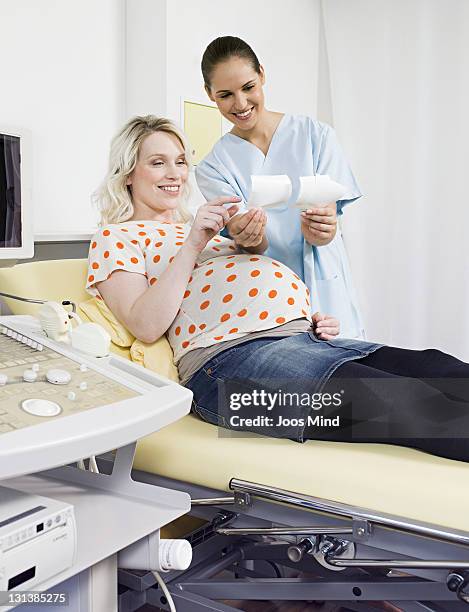 midwife showing pregnant woman ultrasound images - midwife stock pictures, royalty-free photos & images