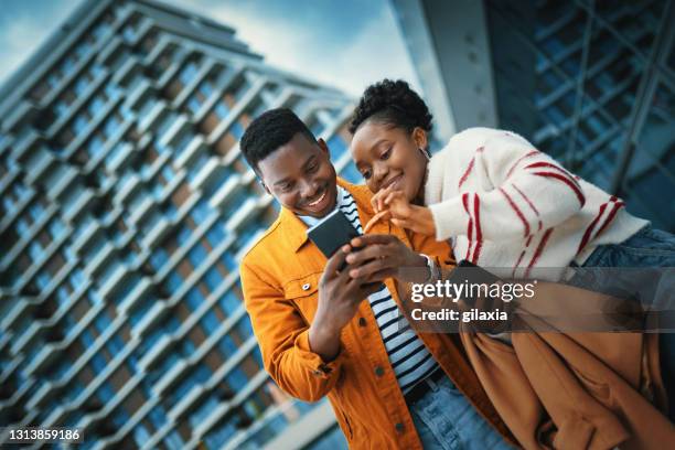 jong afro-amerikaans paar dat van zonnige dag geniet en selfies neemt. - african on phone stockfoto's en -beelden