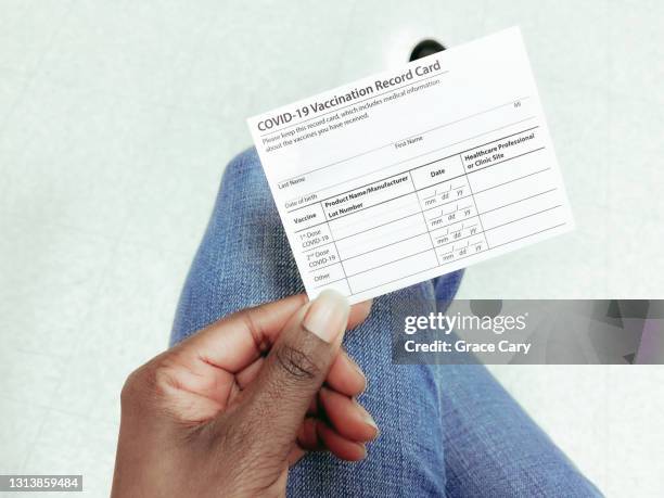 woman holds covid-19 vaccination record card - immunisation certificate stock-fotos und bilder