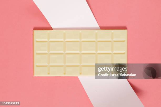 top view of a whole white chocolate bar on a pink background.  sweet and unhealthy food concept. - chocolate bar stock pictures, royalty-free photos & images