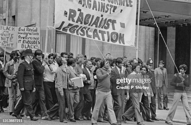 Police presence keeping the peace as demonstrators carry placards reading 'Black and white unite and fight' and 'End patrial immigration preference...