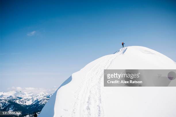 wide shot of mountaineer on snow covered mountain top near squamish - caucasian mountain climber man stock-fotos und bilder
