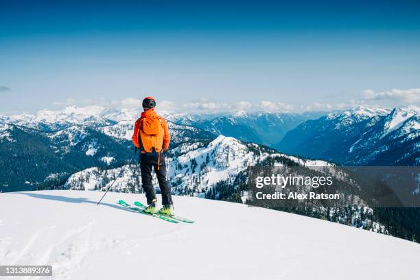 ski mountaineer stands on top of mountain top and looks out at vista view - skiing ストックフォトと画像