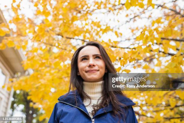 young woman walking outdoors under autumn leaves - fall park stock-fotos und bilder