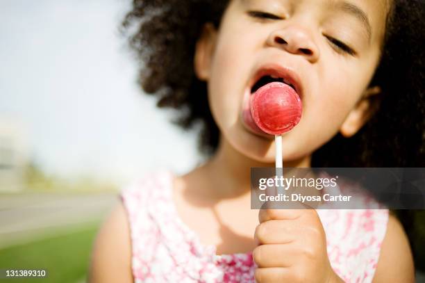 child with afro licking red lollipop - lecca lecca foto e immagini stock