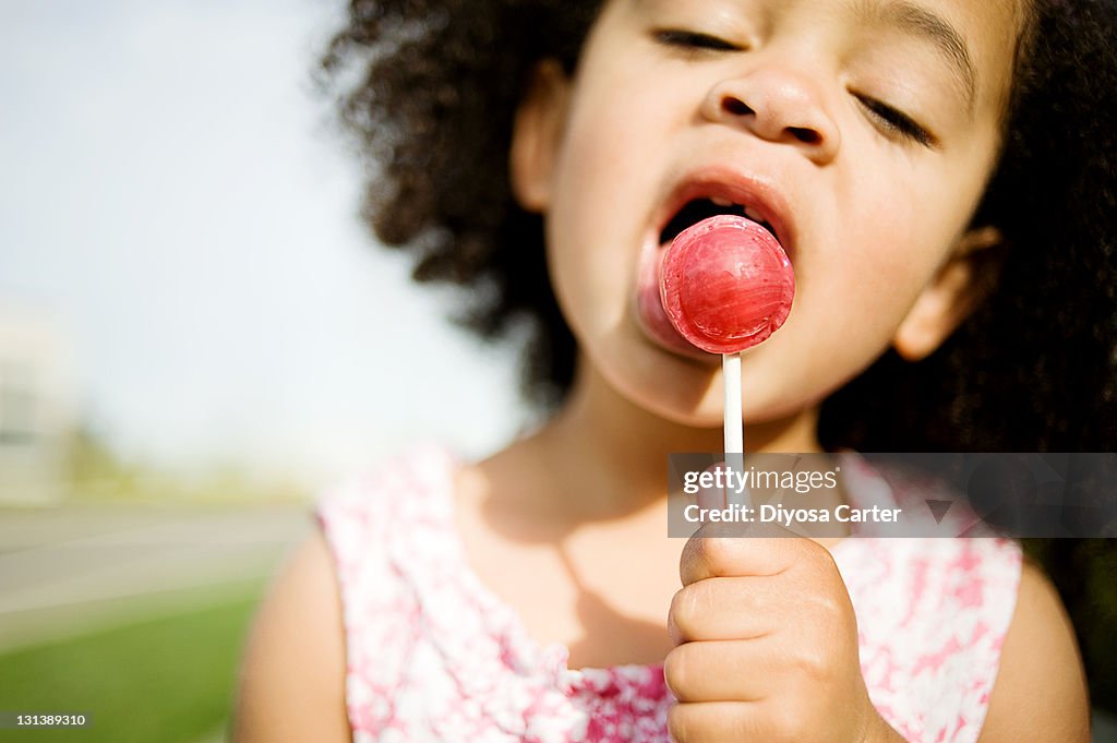 Child with Afro licking red lollipop