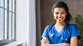 Portrait of african-american female doctor with stethoscope on hospital background. A physician standing with cheerful gesture. Woman nurse wearing doctor uniform with smiling face. Health insurance and physician concept.