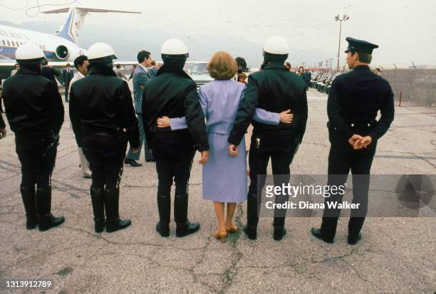 View, from behind, as US First Lady Rosalynn Carter poses for a photo with uniformed police officers on an airport runway, during a stop in support...