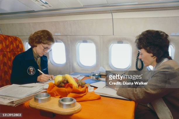 View of US First Lady Rosalynn Carter and Second Lady Joan Mondale as they work at a table in an airplane, en route for a joint appearance in support...