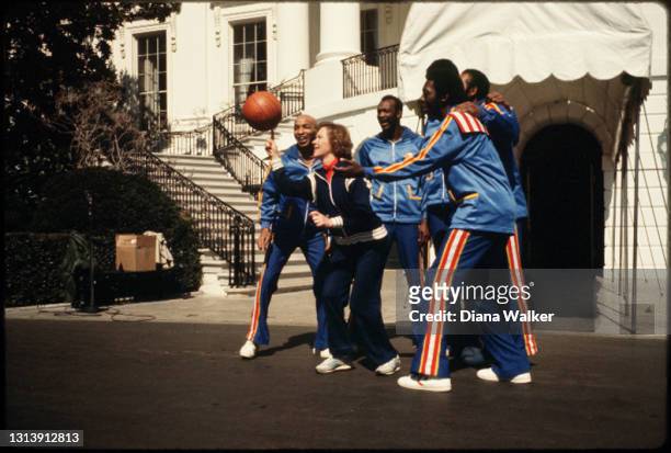 First Lady Rosalynn Carter plays basketball with members of the Harlem Globetrotters outside the White House, Washington DC, March 1980. They are...