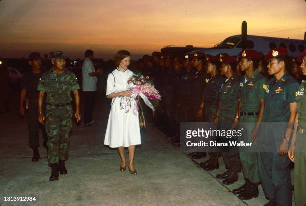 As the sun sets, US First Lady Rosalynn Carter is welcomed, by members of the Thai military, as she arrives at Sakon Nakhon Air Base, Sakon Nakhon,...
