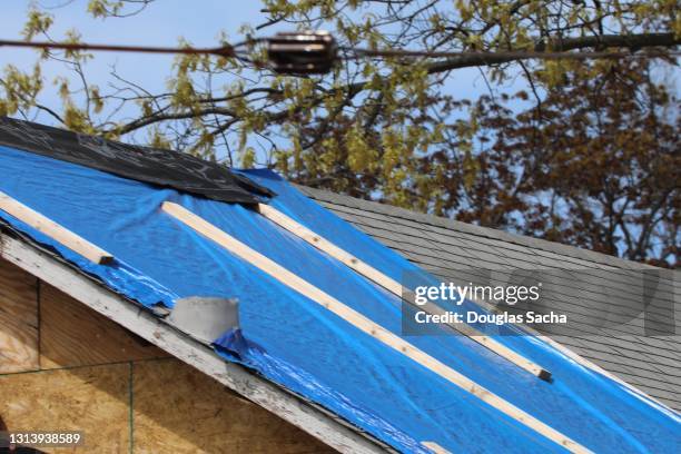 building repair project with plastic tarp covering the roof - tarpaulin fotografías e imágenes de stock