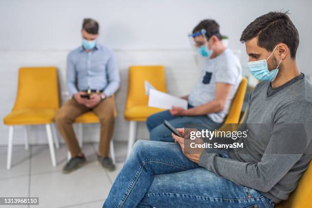 patiënten met gezichtsmaskers in wachtkamer - patients in doctors waiting room stockfoto's en -beelden