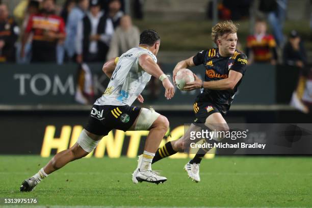 Damian McKenzie of the Chiefs looks to beat the tackle of Devan Flanders of the Hurricanes during the round nine Super Rugby Aotearoa match between...