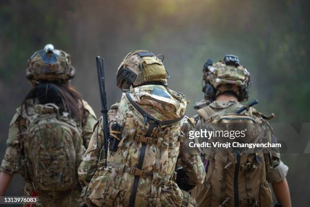 rear of soldiers patrolling along the risky area. - armed forces stock-fotos und bilder