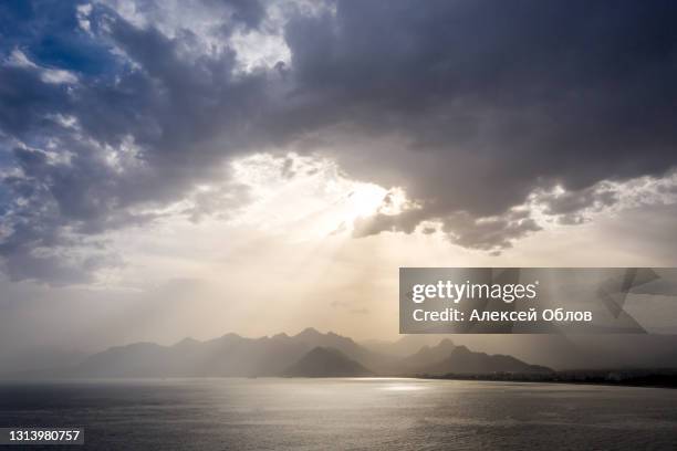 summer landscape with views of the mediterranean coast. layers of mountains on the horizon, rays of the sun breaking through the clouds. evening time before sunset. antalya, turkey - grey boot stock-fotos und bilder