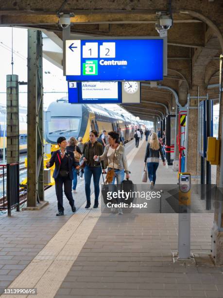 conductor and passengers leaving the platform after arriving at maastricht railway station - railroad conductor stock pictures, royalty-free photos & images