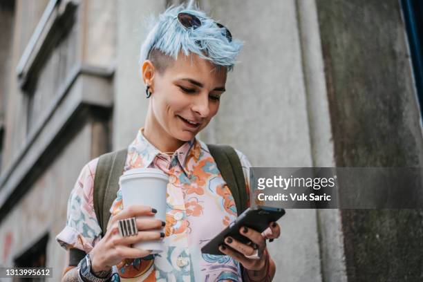 frau hält telefon und kaffee zu gehen - lesbische stock-fotos und bilder